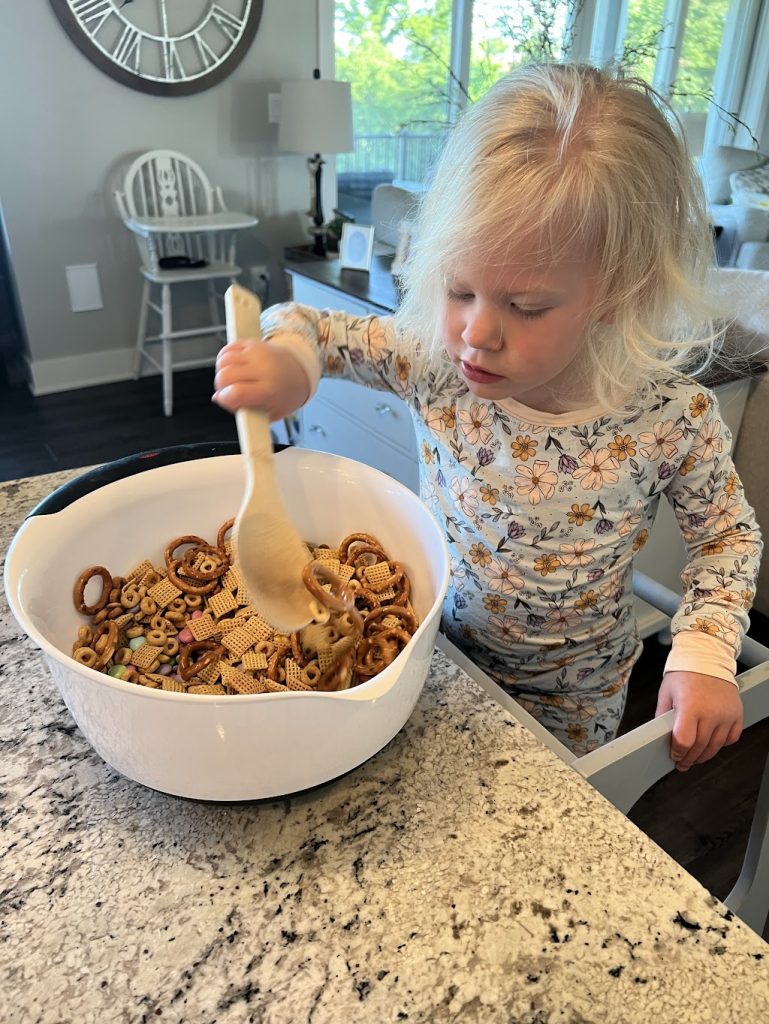 Evie making snack mix